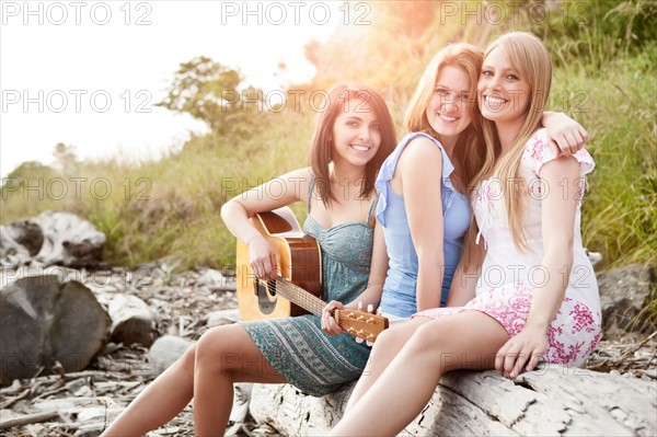 Portrait of young women with guitar on beach. Photo : Take A Pix Media