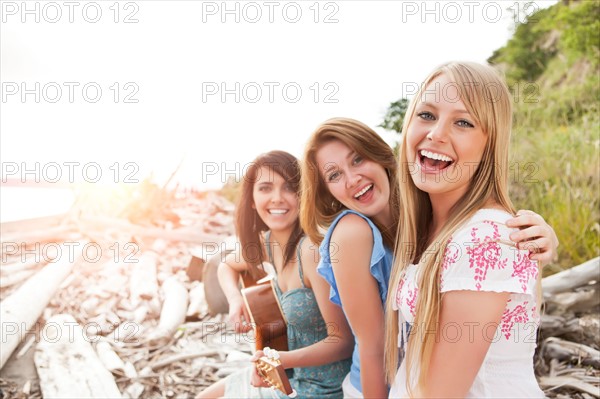 Portrait of young women with guitar on beach. Photo : Take A Pix Media