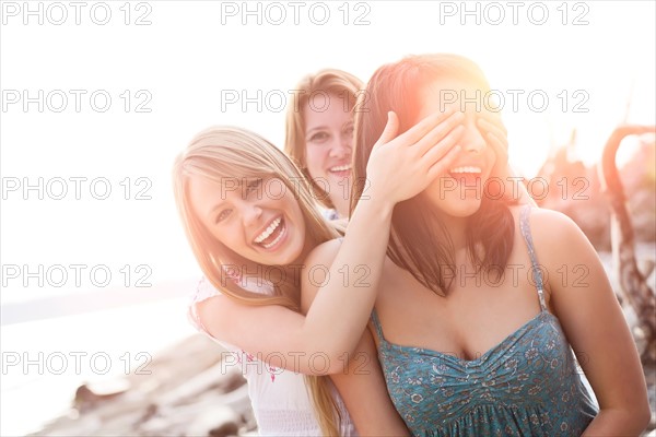 Three young women hanging out, covering eyes and laughing. Photo : Take A Pix Media
