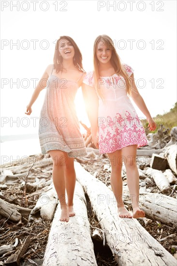 Two young women balancing on logs. Photo : Take A Pix Media