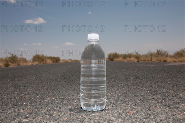 Water bottle sitting in middle of desert road. Photo : Winslow Productions