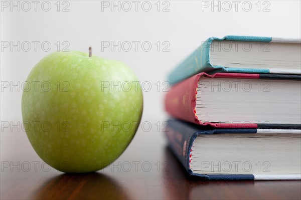 Studio shot of green apple and textbooks. Photo : Winslow Productions