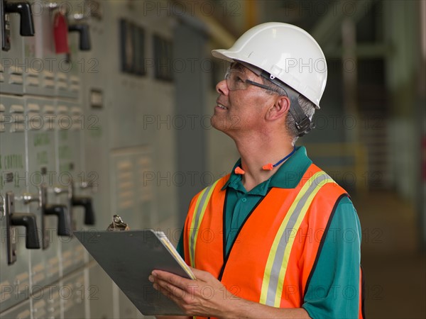 Industrial worker in hard hat writing on clipboard. Photo : db2stock