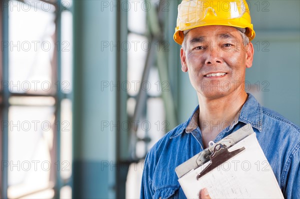 Portrait of man wearing hardhat holding clipboard. Photo: db2stock