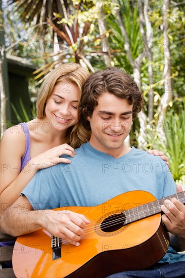 Young couple in park, man playing guitar. Photo : Rob Lewine