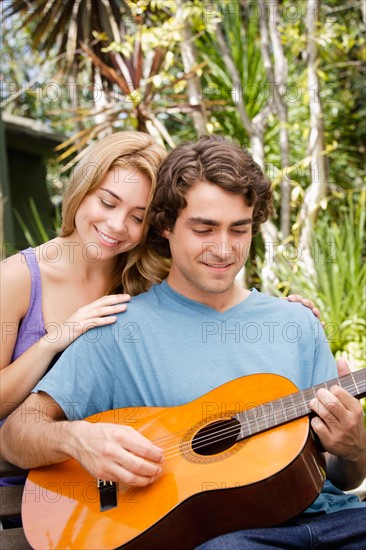 Young couple in park, man playing guitar. Photo : Rob Lewine