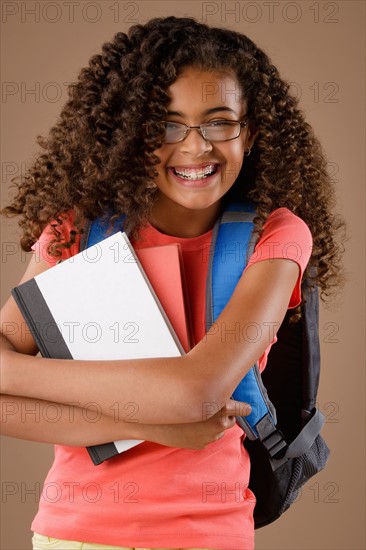 Studio portrait of girl (10-11) with backpack and books. Photo: Rob Lewine