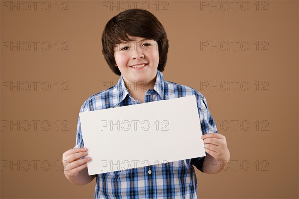 Studio portrait of boy (10-11) holding blank sheet of paper. Photo: Rob Lewine