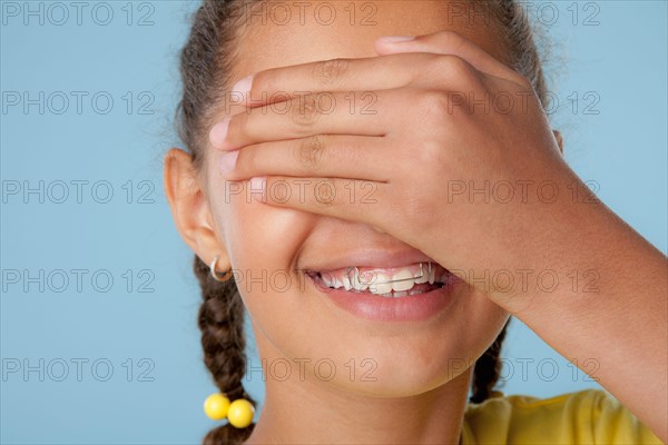 Studio shot of girl (10-11) covering eyes with hand. Photo : Rob Lewine