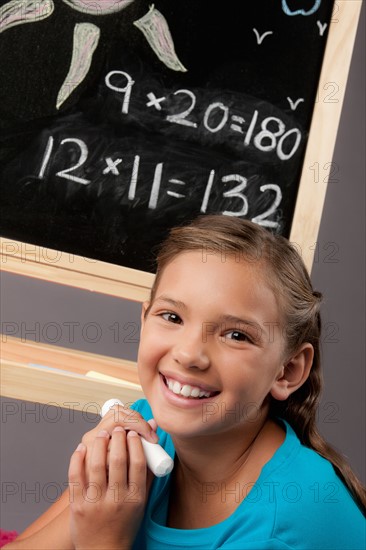 Studio portrait of girl (8-9) next to blackboard. Photo : Rob Lewine