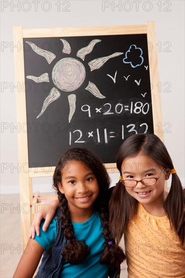 Studio portrait of two girls (8-9) in front of blackboard. Photo: Rob Lewine