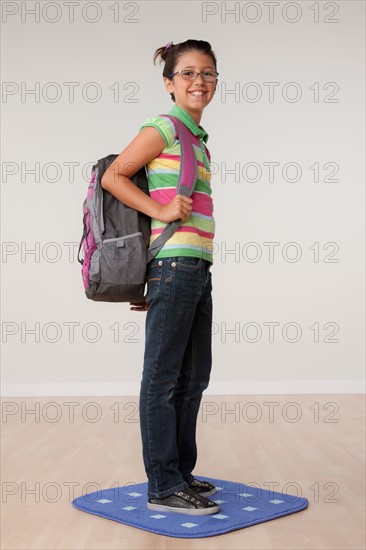 Studio portrait of girl (8-9) carrying backpack. Photo : Rob Lewine