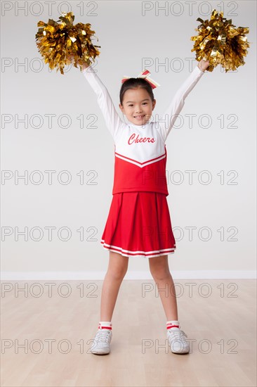 Studio portrait of girl (8-9) cheerleading. Photo : Rob Lewine