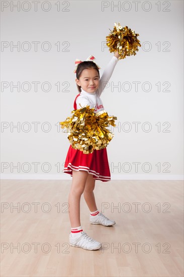 Studio portrait of girl (8-9) cheerleading. Photo : Rob Lewine