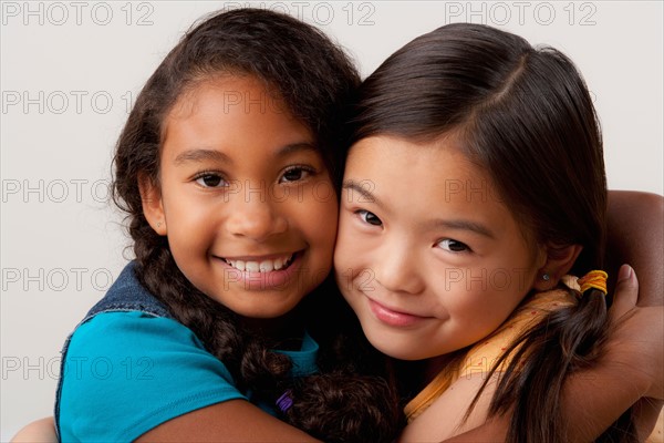 Studio portrait of two girls (8-9) embracing. Photo: Rob Lewine