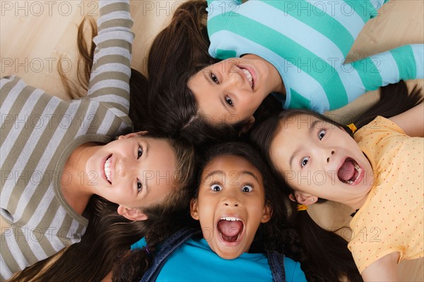 Studio portrait of four girls (8-9) lying on floor. Photo : Rob Lewine