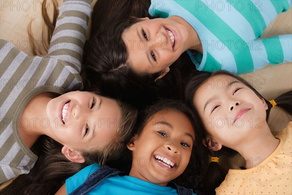 Studio portrait of four girls (8-9) lying on floor. Photo : Rob Lewine