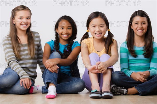 Studio portrait of four girls (8-9) sitting side by side. Photo : Rob Lewine