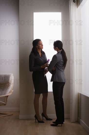 Two business women discussing in office. Photo : Rob Lewine