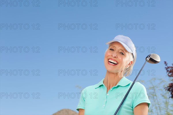 Portrait of mature woman holding golf club. Photo : db2stock