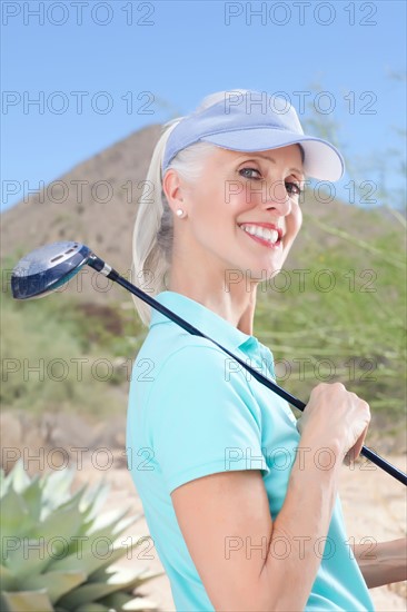 Portrait of mature woman holding golf club. Photo : db2stock