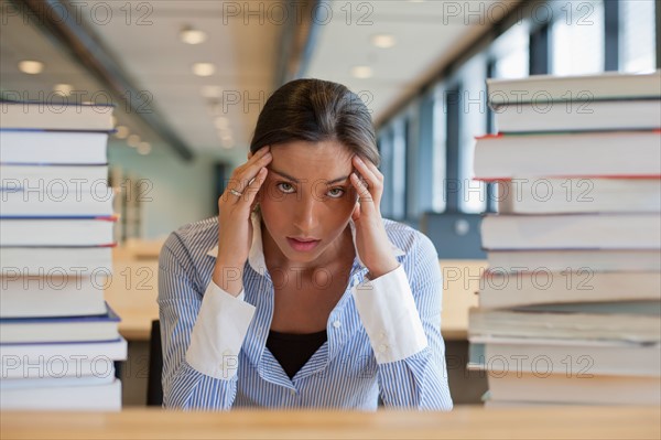 Female student between stacks of books. Photo : Jan Scherders