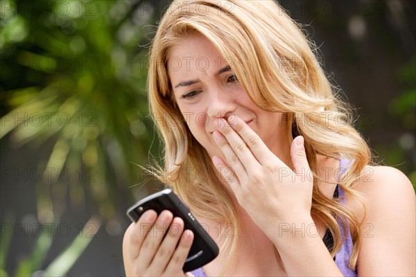 Young woman text-messaging, with facial expression. Photo: Rob Lewine