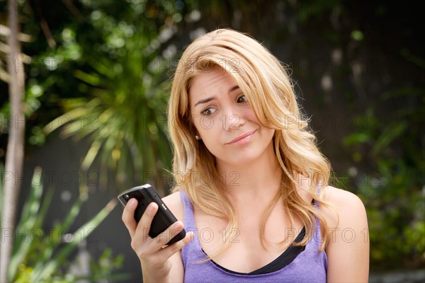 Young woman text-messaging, with facial expression. Photo: Rob Lewine