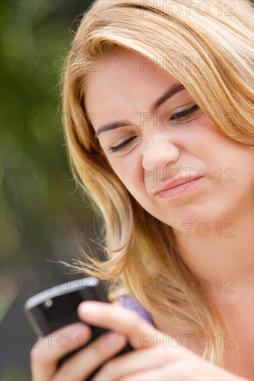 Young woman text-messaging, with facial expression. Photo : Rob Lewine