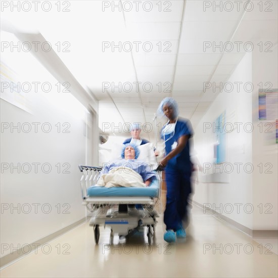 Senior woman being taken to operating room by medical staff.