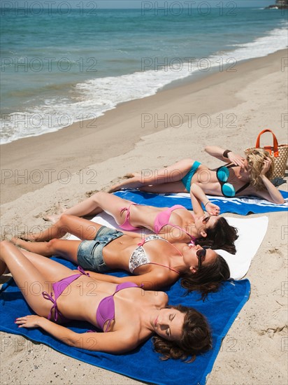 Group of young attractive women sunbathing on sandy beach.