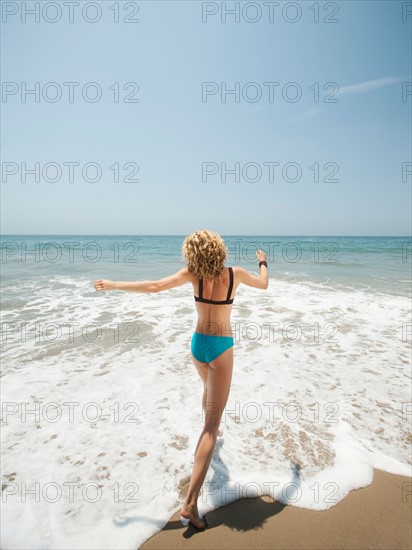 Happy young woman running in to sea.