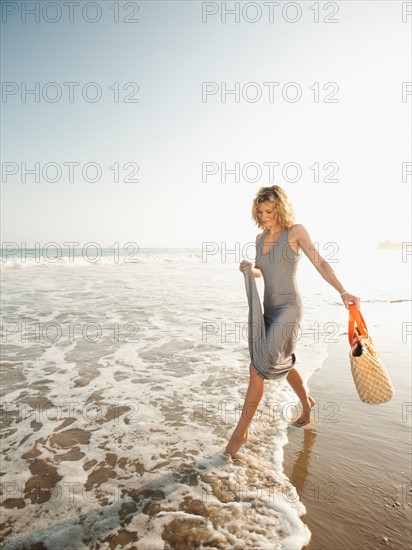 Attractive young woman walking on sandy beach.