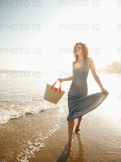 Attractive young woman walking on sandy beach.