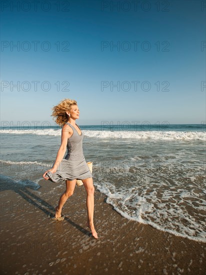 Attractive young woman walking on sandy beach.