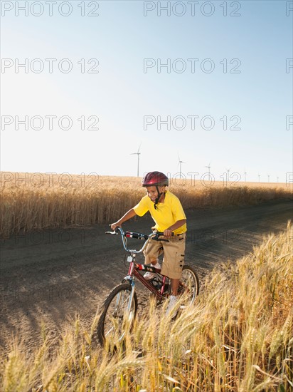 Boy (8-9) cycling along dirt road.