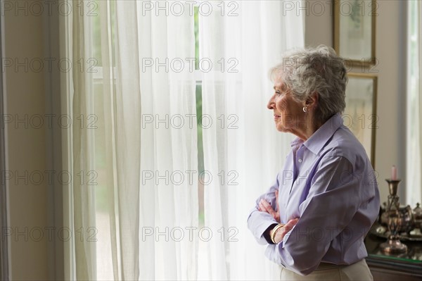 Senior woman looking through window.