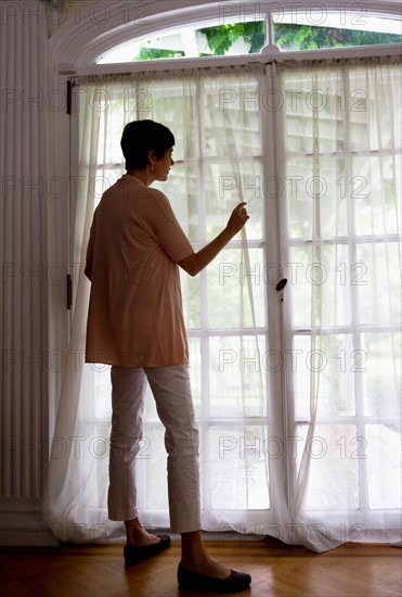 Mature woman looking through window.