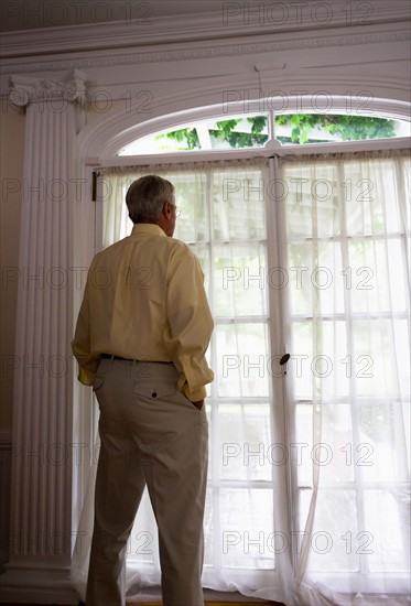 Senior woman looking through window.