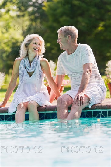 Senior couple at edge of swimming pool.