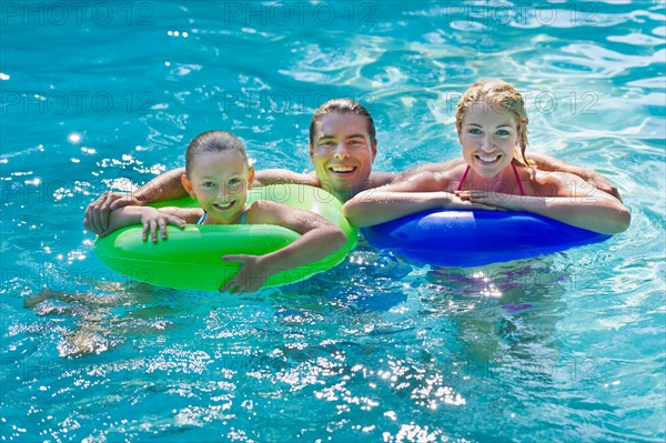 Girl (10-11) with parents in swimming pool.