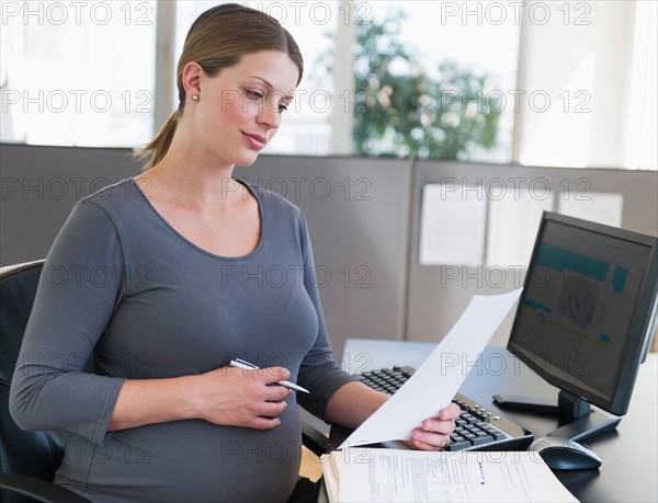 Young pregnant woman working in office.