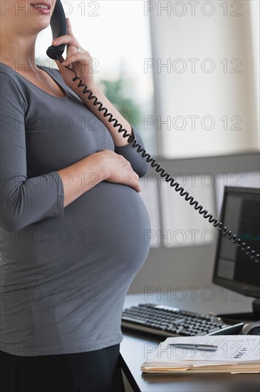 Young pregnant woman working in office.