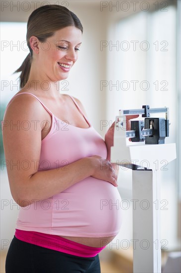 Pregnant woman weighing herself.