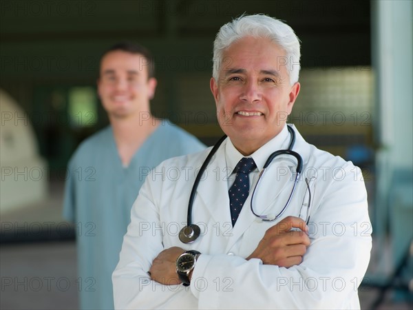 Portrait of senior doctor with orderly in background. Photo : db2stock