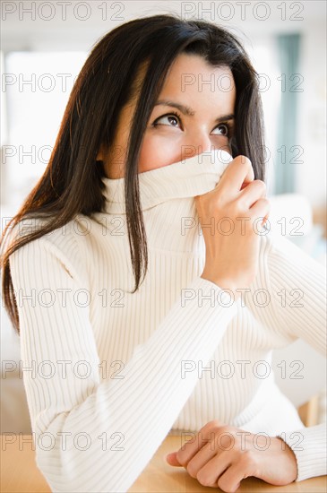 Portrait of woman covering face with turtle neck. Photo : Jamie Grill