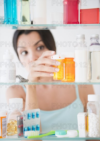 Woman taking medicine from cabinet. Photo : Jamie Grill