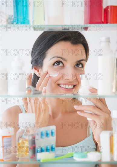 Woman applying lotion on face. Photo: Jamie Grill