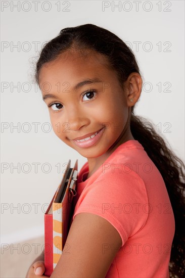 Studio portrait of girl (8-9) holding books. Photo : Rob Lewine