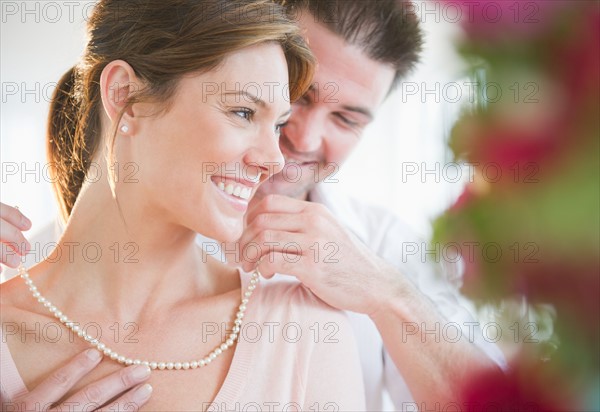 Manputting pearls on hisgirlfriend's neck. Photo : Jamie Grill